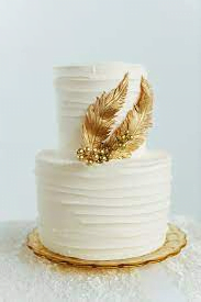 image desc: a white cake with two gold feathers on the front
